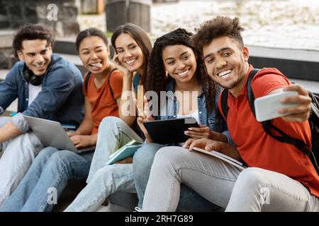 Gruppe internationaler Studenten, die gemeinsam im Freien Fotos auf einem Smartphone machen Stockfoto