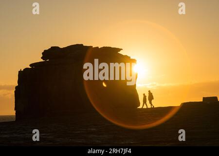 Portland, Dorset, Großbritannien. 14. Aug. 2023. Besucher von Portland Bill, Dorset, schlendern am Pulpit Rock vorbei, während die Sonne untergeht. Kredit: Peter Lopeman/Alamy Live News Stockfoto