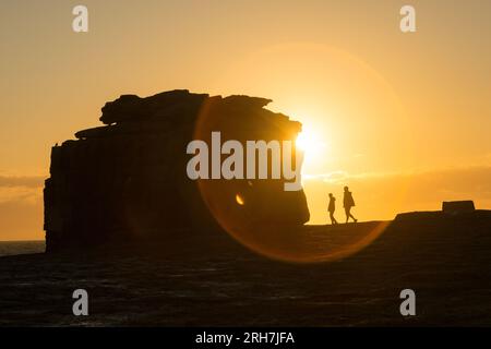 Portland, Dorset, Großbritannien. 14. Aug. 2023. Besucher von Portland Bill, Dorset, schlendern am Pulpit Rock vorbei, während die Sonne untergeht. Kredit: Peter Lopeman/Alamy Live News Stockfoto