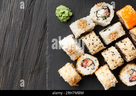 Sushi-Brötchen mit Lachs, Thunfisch, Kaviar, Sesamsamen auf einer schwarzen Steinplatte, Nahaufnahme. Stockfoto