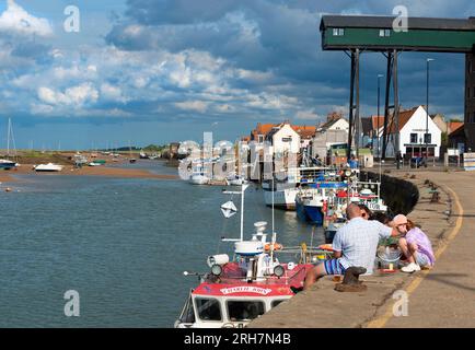 Familien-Krabben am Kai der Ferienstadt Wells-next-the-Sea mit ihren Fischerbooten, die bei Ebbe anlegten. Norfolk, England Stockfoto