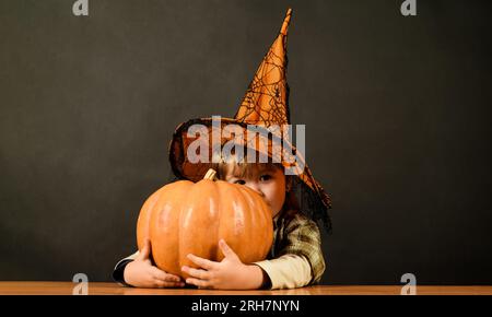 Halloween-Kinder. Lächelnder Junge mit Hexenhut und Halloween-Jack-o-Laterne. Ein kleines Kind im Zauberkostüm mit einem großen Halloween-magischen Kürbis. Familie Stockfoto