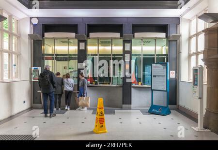 Warteschlange am Ticketschalter des Bahnhofs Lancaster mit einem Fahrgast, der ein Ticket kauft Stockfoto