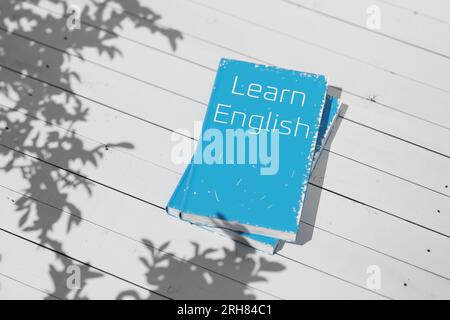 Englisches Lehrbuch auf einem weißen Holztisch. Englisch lernen. Englische Grammatik. Englischsprachiges Lehrbuch zum Sprachenlernen. 3D-Rendering. Stockfoto