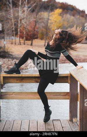 Junge Frau, die ihren Kopf zurückwirft, mit langen Haaren, die um sie herum fliegen. See- und Herbstszene. Stockfoto