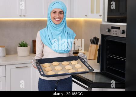 Muslimische Frau, die ein Tablett mit Keksen in der Küche hält Stockfoto