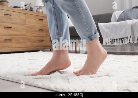 Frau steht auf beigefarbenem Teppich im Zimmer, Schließung Stockfoto