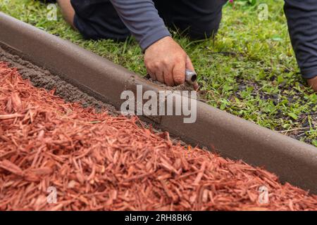 Gartenarbeiter, der eine Grenze nach den HOA-Vorschriften formt Stockfoto