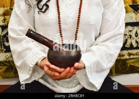 Eine Nahaufnahme einer Frauenhände mit einer tibetischen Klangschale. Stockfoto