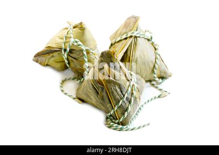 Drei gedämpfte, klebrige Reisklöße aus China, Zongzi oder Bakcang, in Bambusblätter eingewickelt, auf weißem Hintergrund Stockfoto