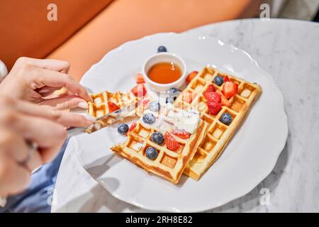 Klassische Wiener Waffeln mit Eis, Beeren und Ahornsirup. Frühstück im Café. Tisch im Restaurant. Stockfoto