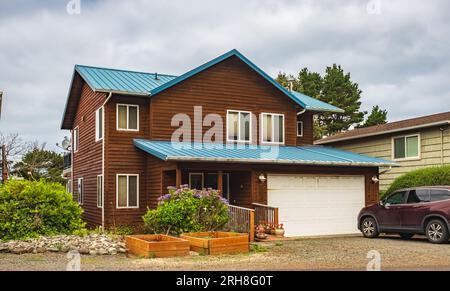 Eine perfekte Nachbarschaft. Häuser in einem Vorort im Sommer. Außenfassade Des Immobiliengebäudes. Große Zollhäuser mit Vorgarten und Auffahrt zur Garage im Stockfoto