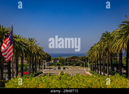 Blick auf den Pazifik und eine breite Straße mit Palmen in der Nähe des Einkaufszentrums Fashion Island in Newport Beach, dem berühmten kalifornischen Reiseziel Stockfoto