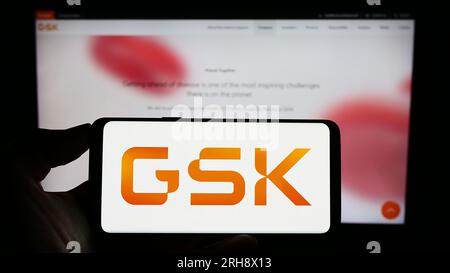 Person, die ein Smartphone mit dem Logo des britischen Pharmaunternehmens GSK plc auf dem Bildschirm vor der Website hält. Konzentrieren Sie sich auf das Display des Telefons. Stockfoto