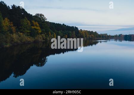 Atemberaubend schöner See in der goldenen Herbstsaison. Magische mehrfarbige Reflexion mit leichten Wellen auf der Oberfläche des Wasserfalles am Abend. Herbstlandschaft farbenfrohe Herbstwälder mit leuchtend gelbroten, orangefarbenen und grünen Baumblättern, die sich in einer stillen Wasseroberfläche des Sees spiegeln Stockfoto