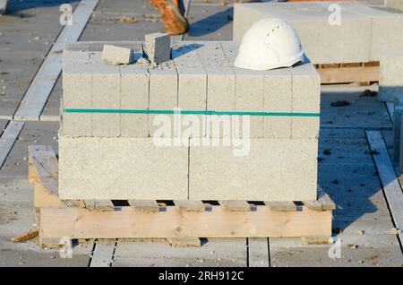 Betonblöcke werden an die Baustelle geliefert und neben dem Arbeitsplatz platziert und sind bereit für Mauerwerk Stockfoto