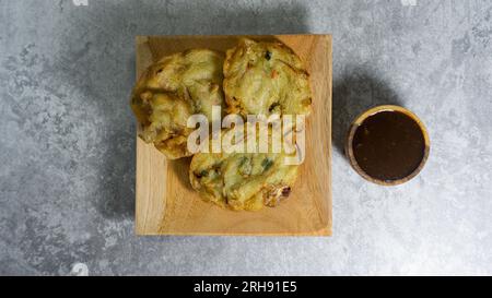 Bakwan wird auf einem Holzteller serviert, und Petis Sauce wird in einer kleinen Holzschüssel serviert. Stockfoto