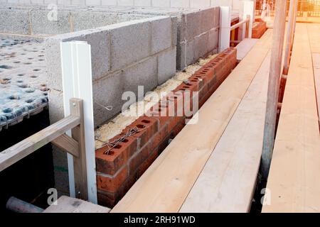 Dämmung der Wände von Neubauten durch Platzierung von Steinwolle in Wandhöhlen als Teil der Energiesparmaßnahmen. Haus mit Mineralwoo isoliert Stockfoto