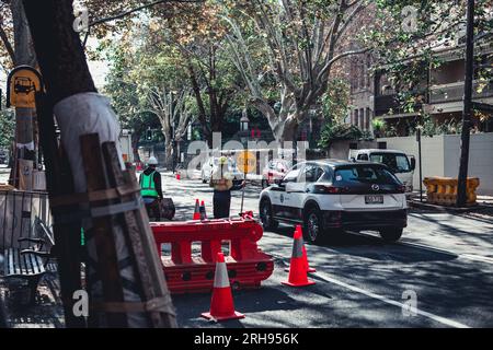 Straßenbauarbeiten entlang der Straßen in Sydney. Ein Lutscher kann gesehen werden, der entgegenkommenden Verkehr lenkt. Stockfoto