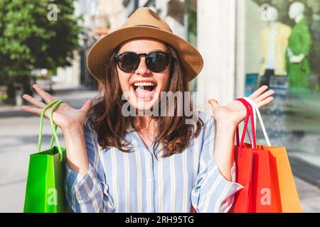 Junge Frau glücklich mit neuen Einkäufen, Straßenverkauf, Modeeinkauf. Stockfoto