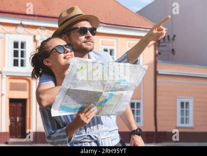 Junge Erwachsene Paare Reisende mit Papierkarte in den Händen, die einen Blick auf die historische Attraktion werfen. Stockfoto