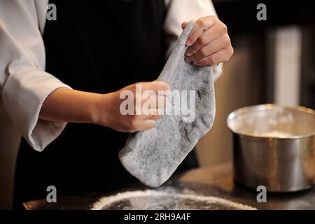 Hände von Pizzaproduzenten kneten Teig Stockfoto