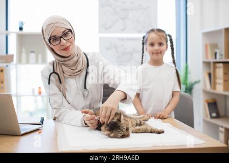 Vet mit Spritze und Tween Girl posiert in der Nähe der Katze auf dem Tisch Stockfoto