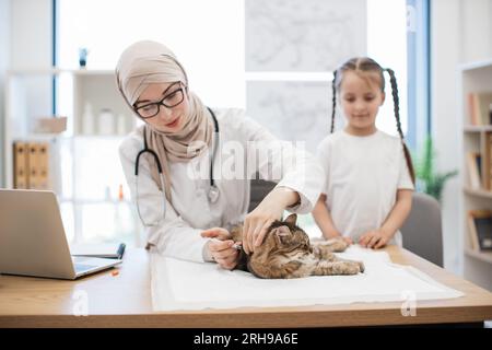 Vet mit Spritze und Tween Girl posiert in der Nähe der Katze auf dem Tisch Stockfoto