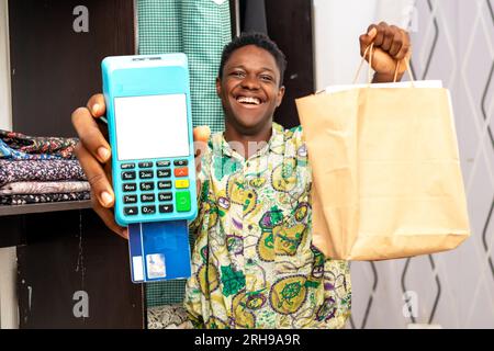 Foto eines schwarzen afrikanischen Lieferers mit Einkaufstasche und POS-Terminal Stockfoto