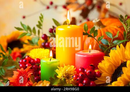 Herbstkonzept mit brennenden bunten Kerzen und Blumen Stockfoto