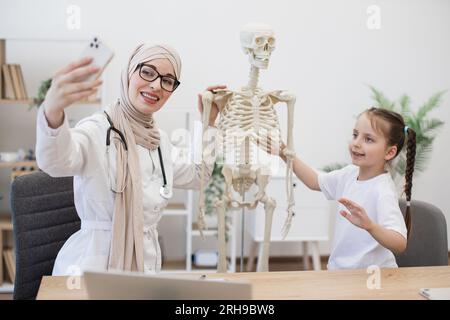 Arzt im Hijab-Selbstbild mit Kind im Büro Stockfoto