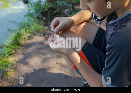 Ein Teenager richtet einen Köder ein, um Fische zu fangen. Sportfischen auf dem Fluss im Sommer. Stockfoto