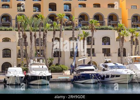 St Julians, Malta - 2. August 2023: Luxus-Motorboote vor Wohnhäusern rund um den Yachthafen in der Portomaso-Siedlung Stockfoto