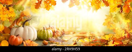 Thanksgiving- oder Herbstszene mit Kürbissen, Herbstblättern und Beeren auf einem Holztisch. Herbsthintergrund mit Kopierbereich. Banner Stockfoto