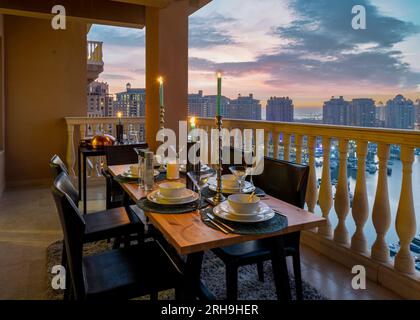 Dinner-Tisch auf dem Dach mit Blick auf den Sonnenuntergang in Pearl Qatar. Blick auf Peral Katar Porto Arabien vom Balkon Stockfoto