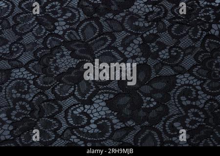 Stoffstruktur. Netzstruktur. Stoffstruktur mit Blumen. Schnurstruktur, Netzgewebe. Schwarzer Synthetikstoff. Kann als Hintergrund verwendet werden Stockfoto