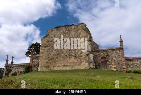 Blick auf die Ruinen des gotischen Friedhofs in der kantabrischen Stadt Comillas, mit einer grünen Wiese und blauem Himmel mit Wolken. Stockfoto