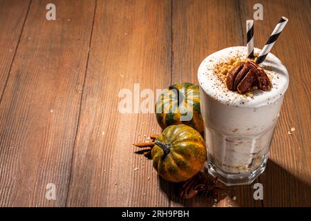 Hausgemachter, beladen Kürbis-Gewürz-Milchshake mit Eis und herber Krümel, in einem Glas mit kleinen Kürbissen-Dekor, Pekannüssen und Gewürzen, gesund f Stockfoto