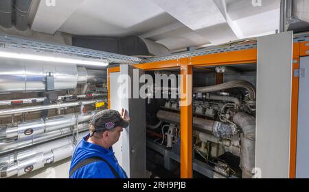 14. August 2023, Sachsen-Anhalt, Halle (Saale): Ein Mitarbeiter des Bauverein Halle untersucht die KWK-Anlage der Genossenschaft im Lutherviertel. Das deutsche Bundesministerium für Bauwesen hatte die Umgestaltung des börsennotierten Genossenschaftsviertels in der Stadt Saale bis Mai 2022 durch ein energisches Stadtkonzept und ein Umbaumanagement unterstützt. Foto: Hendrik Schmidt/dpa Stockfoto