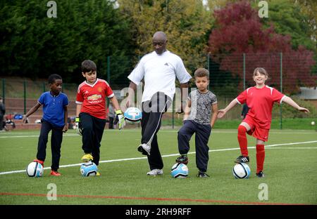 Der ehemalige Fußballspieler Garry Thompson testete das neue 3G-Spielfeld mit einheimischen Kindern in Smethwick in den West Midlands. Stockfoto