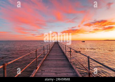 Badesteg mit Fischern während des Sonnenaufgangs, während Sie von der Küste aus, Kalk Coast, South Australia, auf das Meer blicken Stockfoto