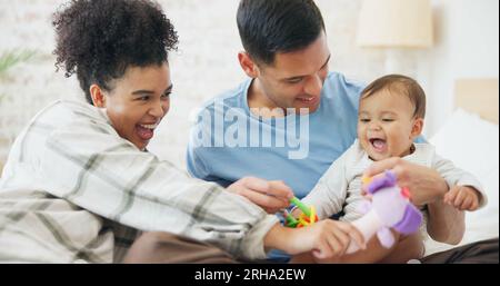 Familie, Paar und Zeit mit Baby, mutter und Vater, die aus Spaß mit Spielzeug spielen, zusammen zu Hause, im Schlafzimmer oder im Kinderzimmer lachen. Neugeborene, Kleinkinder und Stockfoto