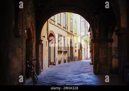 Eine malerische enge Gasse oder Straße mit Geschäften, Geschäften und Apartments im historischen Zentrum von Lucca, Italien in der Toskana. Stockfoto