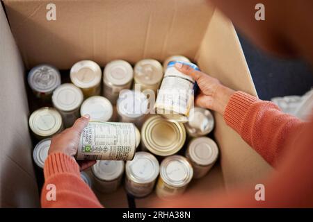 Spenden, Essen in Dosen in Kisten und Hände von Männern, die die Vorräte kontrollieren, Entscheidungen treffen und sich freiwillig mit Hilfe von ngo melden. Unterstützung mit Wohltätigkeit, Wahlmöglichkeiten und Flüchtlingen bei Stockfoto