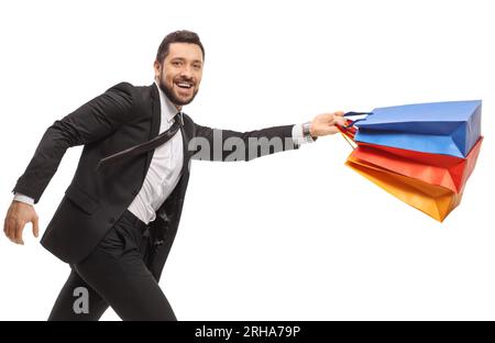 Ein junger Mann in Anzug und Krawatte läuft mit Einkaufstaschen isoliert auf weißem Hintergrund Stockfoto
