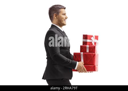 Profilaufnahme eines Mannes im schwarzen Anzug, der einen Stapel Geschenke auf weißem Hintergrund trägt Stockfoto