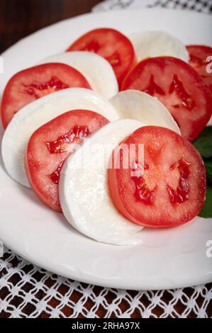 Itaianische vegetarische Speisen, frischer Caprese-Salat mit weißem, weichem italienischen Mozzarella-Käse, rote Tomaten und grünes Basilikum mit Olivenöl. Stockfoto