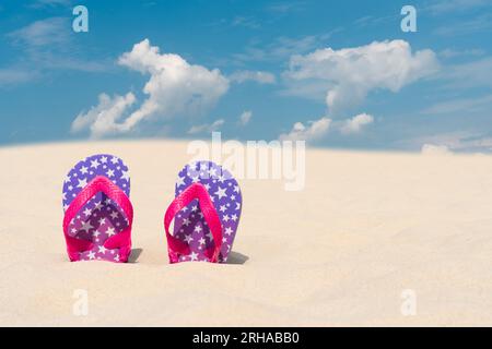 Hausschuhe liegen im Sand am Strand vor dem blauen Himmel. Sommerurlaub, Reise- und Tourismuskonzept. Sommerruhe. Weihnachtszeit Stockfoto