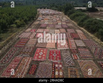 (230815) -- ANTALYA, 15. August 2023 (Xinhua) -- Dieses Luftfoto, das am 15. August 2023 aufgenommen wurde, zeigt handgewebte türkische Teppiche, die auf weiten Feldern verlegt werden, um dem Sonnenlicht im Dosemealti-Bezirk, Provinz Antalya, T¨¹rkiye, ausgesetzt zu sein. Diese Technik, türkische Teppiche zu sonnen, ist eine Methode, die in der Antike verwendet wurde, um ihre Farben weicher zu machen und Keime zu eliminieren, die sie enthalten könnten. Der Bezirk selbst ist das Zentrum handgewebter kleiner Teppiche, die mit natürlichen Farbstoffen aus Pflanzen gefärbt sind. Die riesigen Felder der Bauern verwandeln sich in einen Ort für Teppiche, die nach der Sommerernte vor ihrem Verkauf auf die letzte Stufe gebracht werden Stockfoto