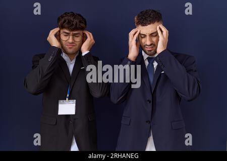 Zwei hispanische geschäftsmänner, die Geschäftskleidung tragen, mit der Hand am Kopf gegen Kopfschmerz wegen Stress. Migräne leiden. Stockfoto